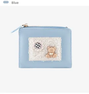 Detail of blue cartoon wallet featuring a plush bear and houndstooth flower decoration