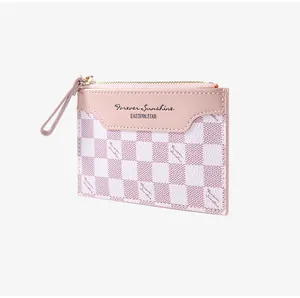 Detail of pink checkerboard card holder featuring zipper closure and leather patch text