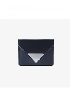 Detail of a minimalist black leather folding wallet with a triangle silver metal accent