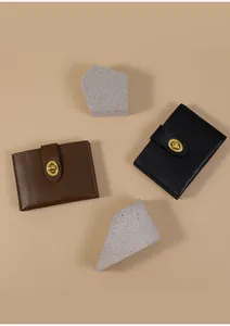 Detail van minimalistische leren portemonnees met gouden draaisluiting in bruin en zwart