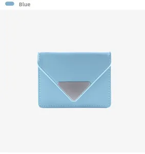 Detail view of light blue envelope wallet with silver triangle metal logo and fine stitching