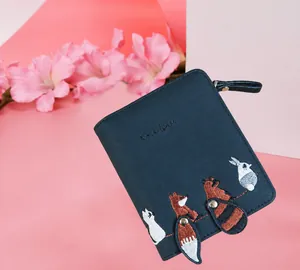 Dettaglio del portafoglio in pelle blu navy con ricami di animali e graziosa nappa
