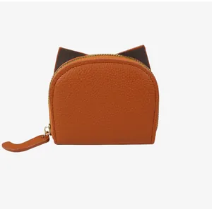 Détail du porte-monnaie en cuir marron avec oreilles de chat et fermeture éclair dorée