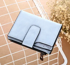 Détail du portefeuille court bleu clair mat avec poche zippée dans un panier blanc