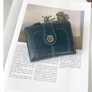 Close-up of vintage dark teal faux leather wallet with hollow patterns and daisy clasp