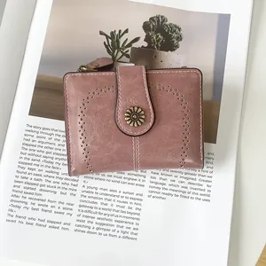 Detail of vintage pink wallet with floral clasp and hollowed-out patterns on a magazine