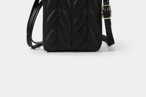 Gros plan du sac de téléphone matelassé noir avec coutures en V et boucle dorée
