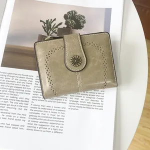 Detail of vintage bi-fold wallet with olive green leather texture and daisy buckle