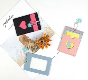 Three leather card holders in pastel colors with flower charms on white background