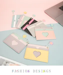 Slim macaron leather card holder with heart window and floral charm on a pastel desk
