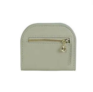 Detail of the semi-circular leather coin purse featuring a textured finish and golden zipper