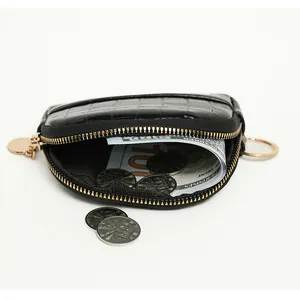 Detail of black faux crocodile skin coin purse with gold zipper and coins inside