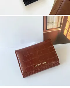 Detalle macro de la cartera de cuero marrón oscuro con patrón de cocodrilo y letras doradas