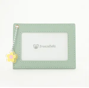 Detail of mint green leather card holder with gold eyelet and yellow flower charm