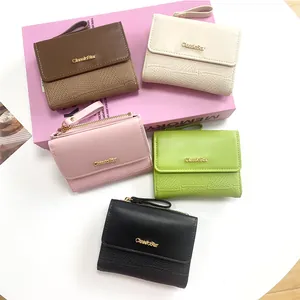 Detail of short wallets in five colors with zip puller and metal logo on a pink box