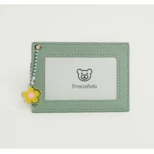 Detail of light green faux leather card holder with clear window and yellow flower charm