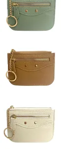 Detailed view of three pebbled leather mini wallets with gold hardware and keychains