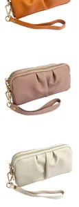 Detail of multi-compartment wristlet bags in orange, pink, and beige with gold zippers