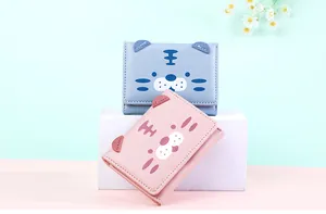 Detail view of pink and blue cartoon tiger PU leather wallets on minimalist stand