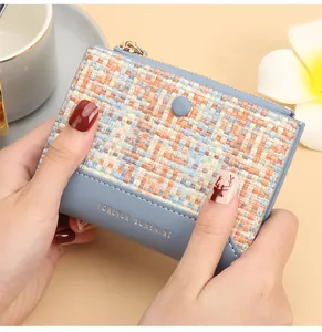 Détail d'un mini portefeuille bleu clair en cuir et tweed tenu à la main pour le style