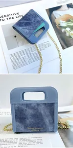 Detalle de mini bolso bandolera de mezclilla azul con cadena dorada y asa calada moderna