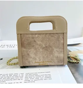 Detalle de un bolso bandolera beige texturizado con cadena dorada y letras de moda