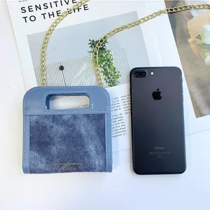Mini bolso bandolera de mezclilla con cadena dorada y asa elegante junto al teléfono
