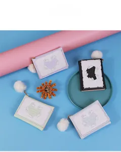 Flat lay of cute bunny trifold wallets in four colors with fluffy white pom pom charms