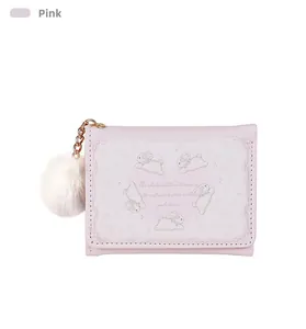 Pink tri-fold wallet featuring white bunny patterns and a fluffy white pompom charm