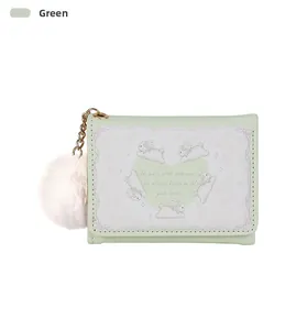 Detail of green tri-fold wallet with rabbit illustration and soft pink pompom charm