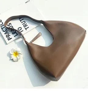 Detail view of a vintage brown leather hobo bag with a minimalist half-moon shape