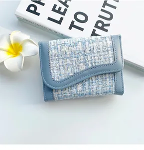Dettaglio portafoglio in tweed blu e bianco con patta a onde e rifiniture in pelle