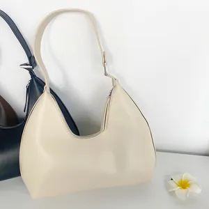 Chic cream and black vegan leather crescent hobo bag with adjustable strap and metal hardware
