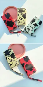 Top view of cow print long wallets in red, yellow and green with wrist straps