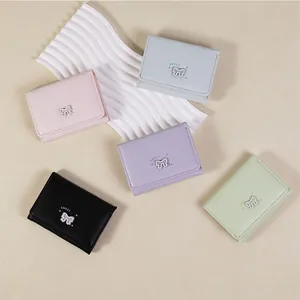Vue à plat de cinq portefeuilles en cuir avec nœud papillon en rose, bleu, violet, vert et noir
