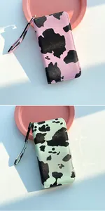 Detail of cow print long wallets in pink and mint green with wristlet and zipper