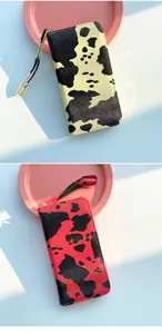 Detail of cow print long wallets with wrist straps and smooth metal zipper closure