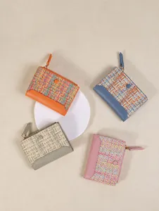 Dettaglio di quattro portafogli intrecciati in vari colori con cerniera a L e logo