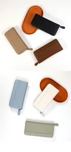 Detailed collection of long zip wallets in six pastel colors on decorative wooden trays