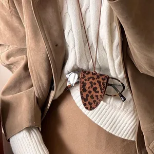 Detail of leopard print leather sunglass holder with elegant stitching on a sweater