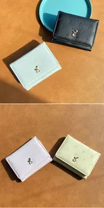 Gros plan de portefeuilles pastel avec gaufrage carotte et fermoir métallique lapin doré