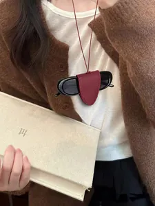 Detail of dark red leather sunglasses holder with stitching and black oval sun shades