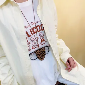 Close-up of leopard print leather glasses pouch with brown lanyard worn by a model