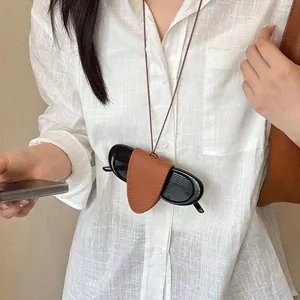 Detail of brown leather neck-hanging sunglasses holder on a white striped shirt