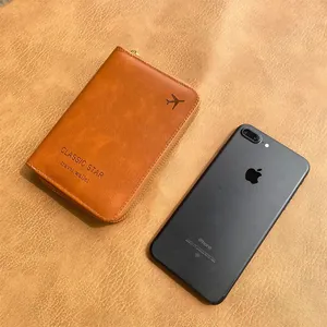 Brown leather RFID travel wallet with zipper and airplane logo next to a smartphone