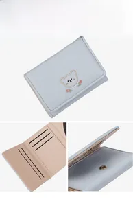 Detail showing embroidered bear design and multiple card slots on light blue PU leather wallet