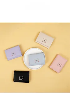 Flat lay of five colorful PU leather bear embroidery tri-fold wallets on a light background