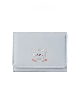 Detail of light blue PU leather wallet featuring a cute cartoon bear embroidery and flowers
