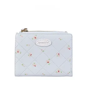 Détail d'un petit portefeuille bleu clair à motif floral rose et texture matelassée