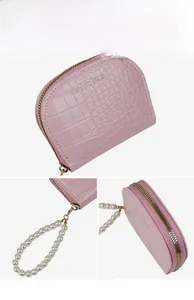 Détails d'un porte-cartes rose à motif crocodile avec bracelet en perles et zip en métal